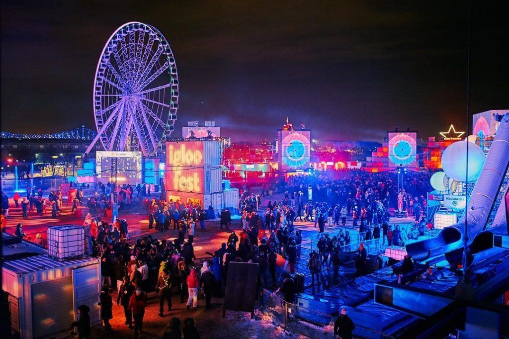 Vue panoramique d’Igloofest à Montréal en hiver, scène principale, installations lumineuses et foule rassemblée au Vieux-Port.