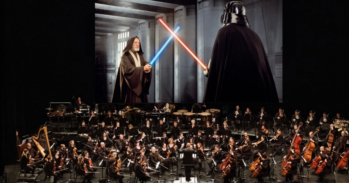 Orchestre symphonique jouant devant un écran géant projetant le film Star Wars à la Place des Arts.