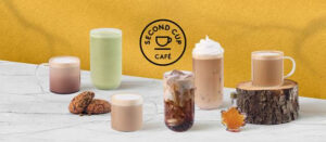 Verre de Dirty Soda Fizz Érable Crème de Second Cup avec de la glace et une touche de crème, entouré de décorations hivernales.