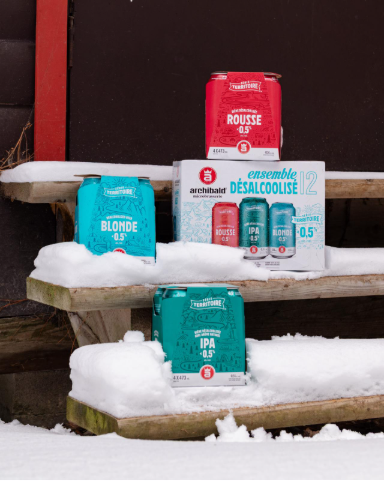 Assortiment de bières sans alcool Série Territoire d'Archibald (Blonde, Rousse, IPA) posées sur des marches en bois enneigées.