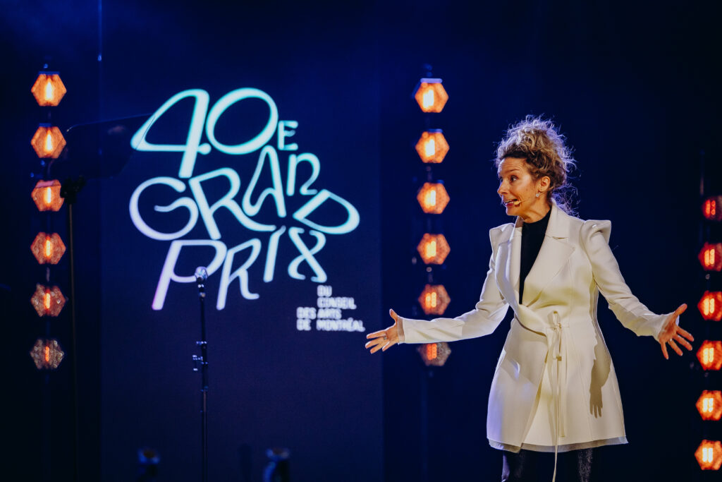 L'animatrice Édith Cochrane sur la scène du Palais des congrès pour le 40e Grand Prix du Conseil des arts de Montréal, entourée des lauréats de la soirée.