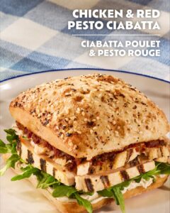 Chicken and red pesto ciabatta sandwich with greens on a plate (multi-seed bread).