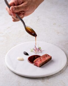 Le chef Chele Gonzalez et l'équipe du Fairmont Le Reine Elizabeth préparant une assiette gastronomique pour les festivités de la course automobile.