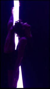 Two silhouettes in a dark scene, one reaching up to grasp a glowing vertical light strip." (informative alt)