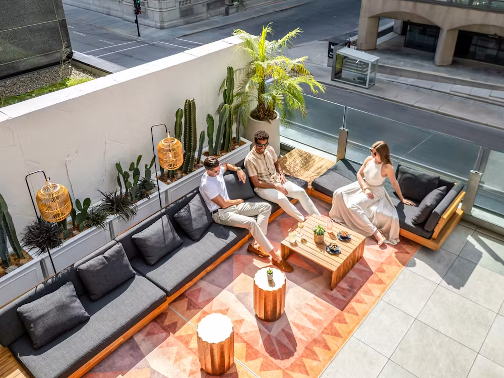 Terrasse du bar Nacarat à l'hôtel Fairmont Le Reine Élizabeth à Montréal avec plantes tropicales et vue sur le centre-ville.