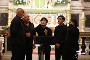 5 chanteurs corses en cercle autour d'un micro dans une église
